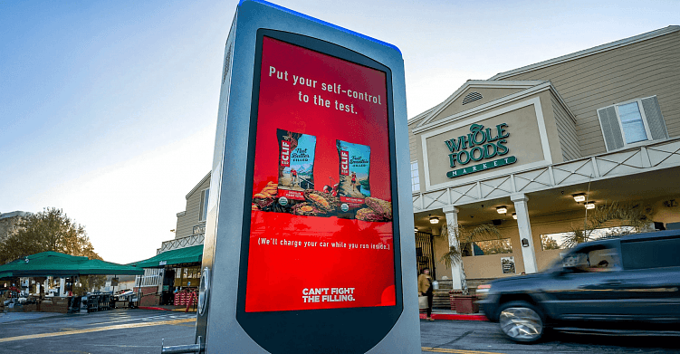 Реклама электрозаправки возле продуктового магазина. Перевод: «Зарядим вашу машину, пока вы будете внутри». Источник: vistarmedia.com