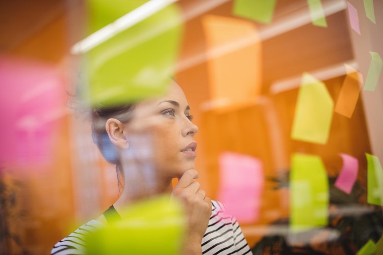 Beautiful female executive reading sticky notes in office